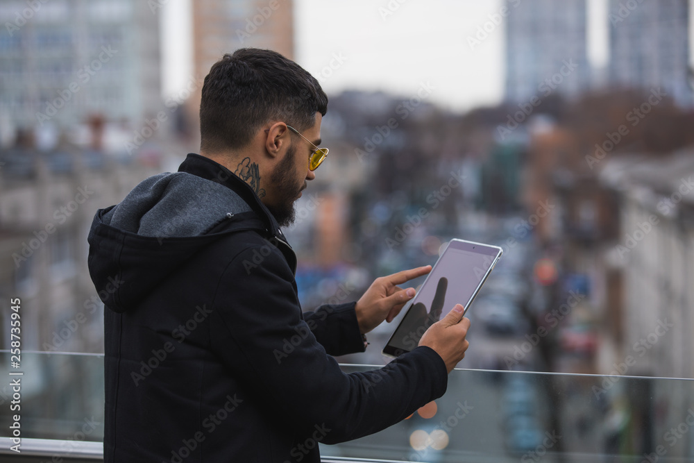 Young stylish man reading book holding tablet pc in city Young stylish man reading book holding tablet pc in city