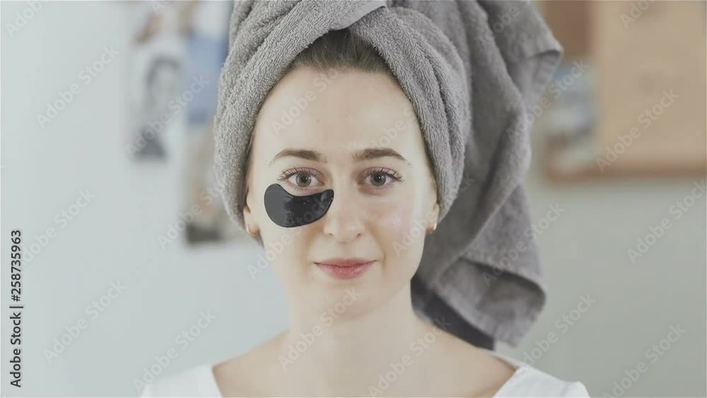 Woman with towel on head imposes under eyes patches of a refreshing Collagen hydrating mask. Woman with towel on head imposes under eyes patches of a refreshing Collagen hydrating mask.