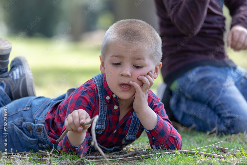 Active boy pointing wooden stick up while walking in spring park,Child boy having fun playing outdoor activity