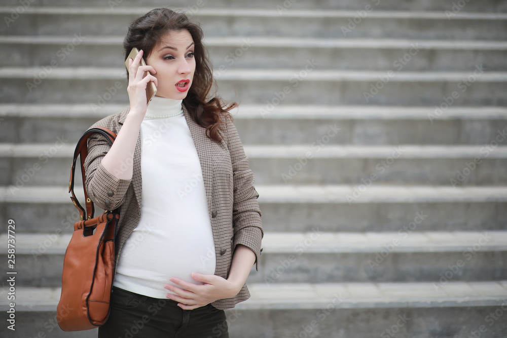 Pregnant woman talking on the phone in the street Pregnant woman talking on the phone in the street