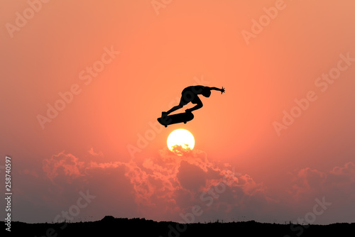 Silhouette of skateboarder young teenager man on sunset background. © patanasak