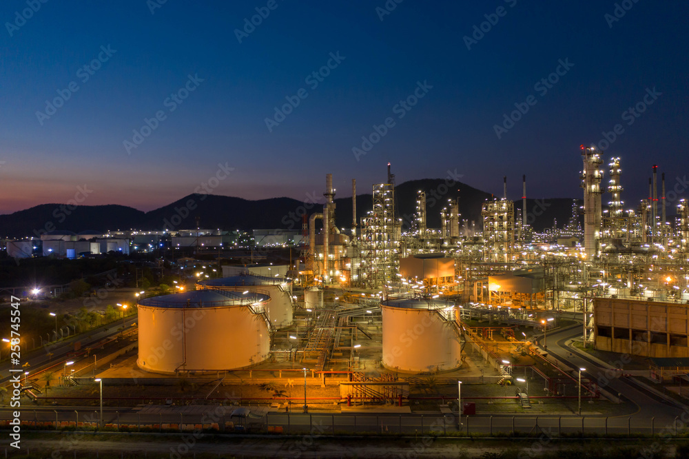 Fototapeta premium Aerial view. Oil refinery factory and oil storage tank at twilight and night. Petrochemical Industrial.
