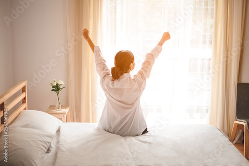 Woman stretching in bed after waking up