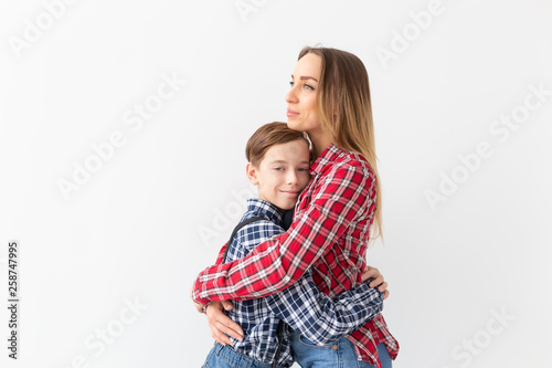 mothers day, children and family concept - cute teen boy with his young mother at home