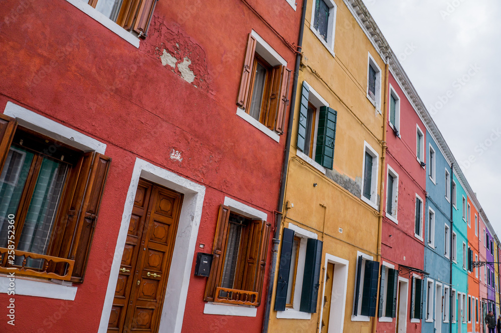 Naklejka premium Coloured yellow and red house wall with windows on Murano Island in Venice Italy