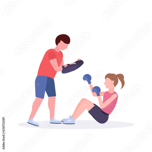sportswoman boxer doing boxing exercises with personal trainer girl fighter in blue gloves working out on floor fight club healthy lifestyle concept flat white background