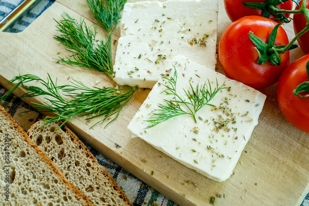 white cream cheese with herbs and spices on a wooden Board decorated with fresh dill, slices of bread and ripe tomatoes white cream cheese with herbs and spices on a wooden Board decorated with fresh dill, slices of bread and ripe tomatoes