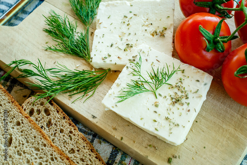 white cream cheese with herbs and spices on a wooden Board decorated with fresh dill, slices of bread and ripe tomatoes
