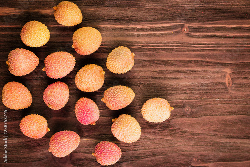 Fresh organic lychee fruits on brown wooden background. photo