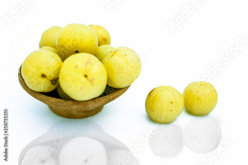 Raw organic amla or indian gooseberry in a clay bowl isolated on white along with its reflection. photo