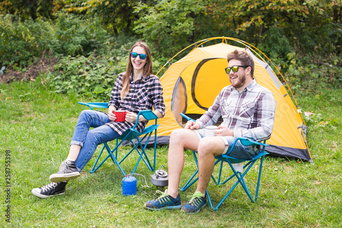 People, tourism and nature concept - Cute couple sitting near yellow tent