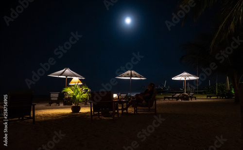 Lighted outdoor restaurant in Bali with full moon on dark sky