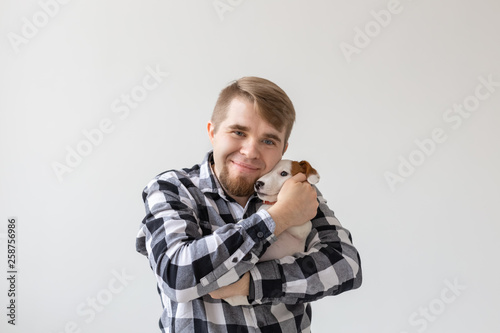 people, pets and animals concept - close up of young man holding jack russell terrier puppy on white background © satura_