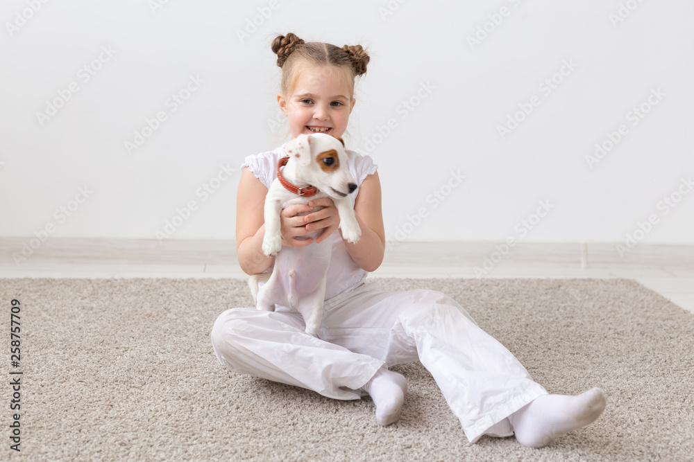 Dogs, children and pets concept - little child girl sitting on the floor with cute puppy Dogs, children and pets concept - little child girl sitting on the floor with cute puppy