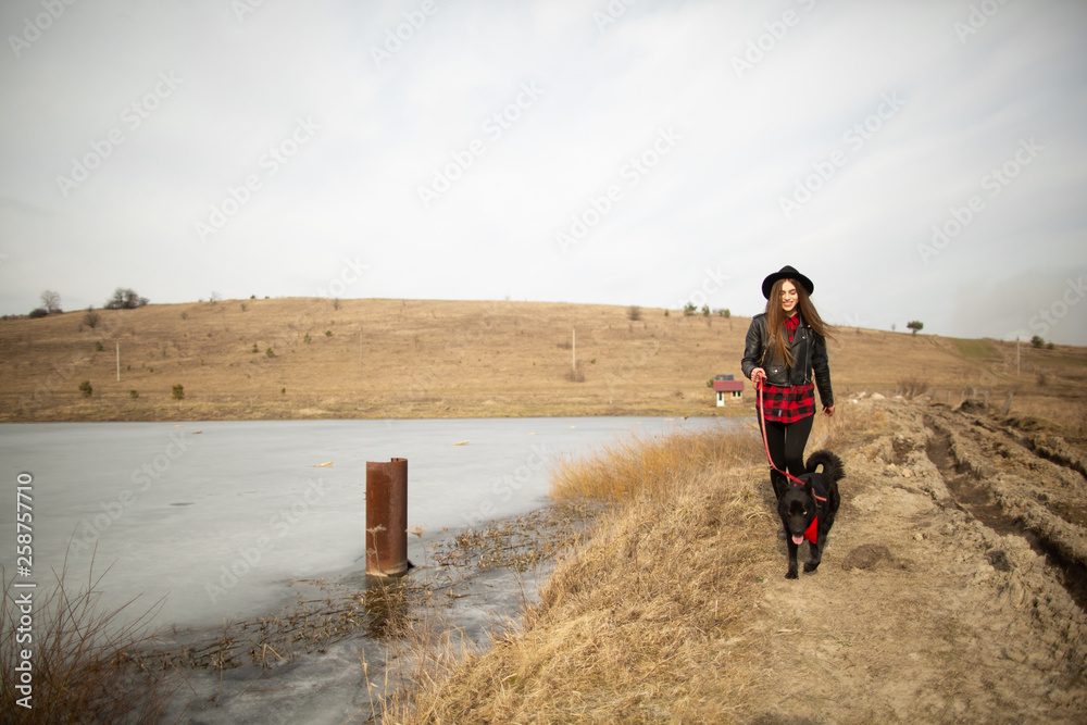 A young girl walks with a dog on the shore of a lake