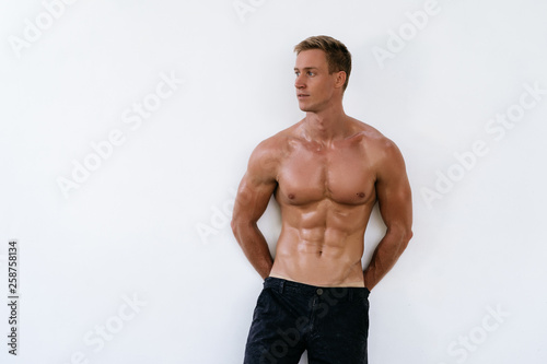 Sexy athletic man with naked torso on white background. Fashion portrait of sporty healthy guy