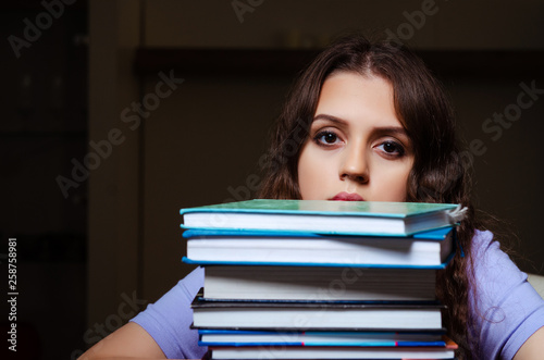 Young female student preparing for exams late at home 