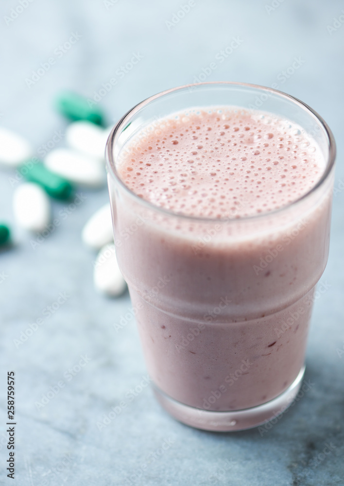Glass of Protein Shake with milk and raspberries. BCAA amino acids and L - Carnitine capsules in background. Sport nutrition. Bright tone background. Close up. Copy space. Glass of Protein Shake with milk and raspberries. BCAA amino acids and L - Carnitine capsules in background. Sport nutrition. Bright tone background. Close up. Copy space.