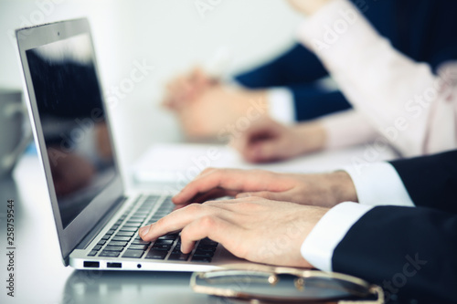 Group of business people working together in office. Man hands typing on laptop computer