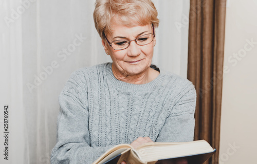 Senior woman is reading book in home. Leisure time on retirement.