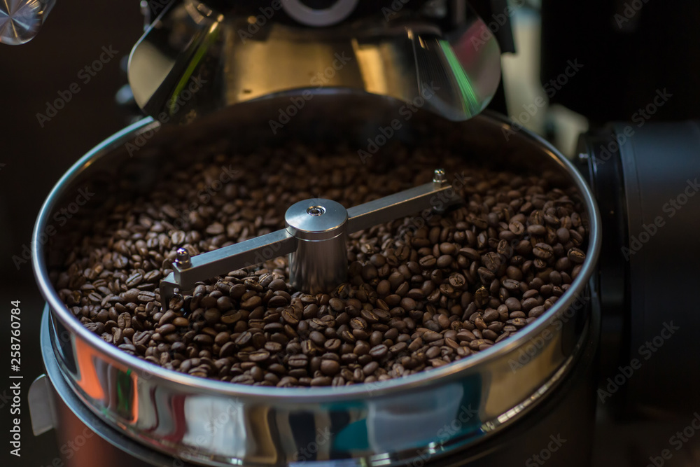 Freshly roasted aromatic coffee beans in a modern coffee roasting machine. Fresh Coffee Beans - Freshly roasted spinning cooler professional machine. Mixing roasted coffee.