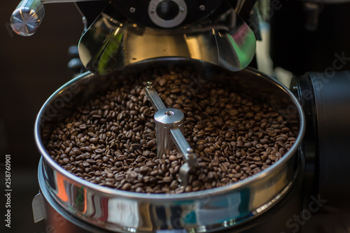 Freshly roasted aromatic coffee beans in a modern coffee roasting machine. Fresh Coffee Beans - Freshly roasted spinning cooler professional machine. Mixing roasted coffee.