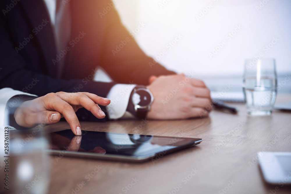Fototapeta premium Group of business people or lawyers work together at meeting in office, hands using tablet and making notes close-up. Negotiation and communication concept