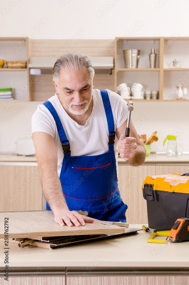 Aged contractor repairman working in the kitchen Aged contractor repairman working in the kitchen
