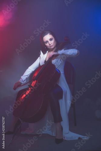 Beautiful woman in a white coat plays the cello