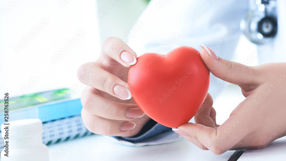 Female medicine doctor hold in hands red toy heart close -up. Cardio therapeutist student education concept