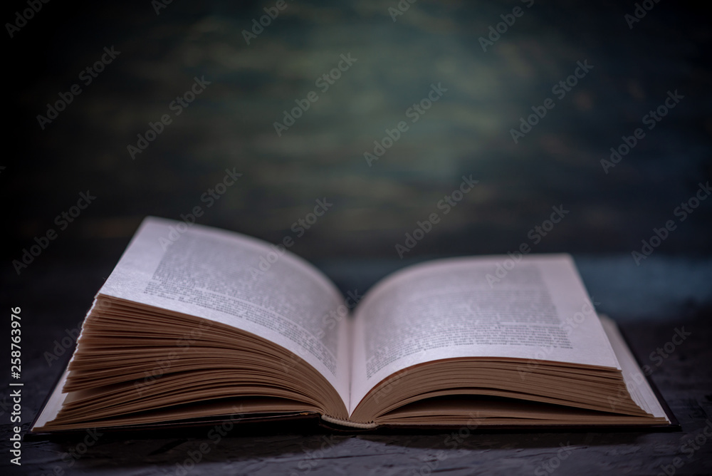 Open book on a stack of books on a table on a dark background. Education  and reading of paper books Stock Photo | Adobe Stock