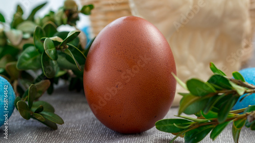 Świąteczne jajko w otoczeniu koszyka i bukszpanu.