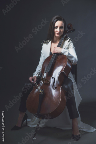 Beautiful woman in a white coat plays the cello