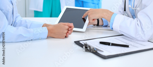 Doctor and patient discussing something  just hands at the table  white background. Physician pointing into tablet screen