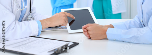 Doctor and patient discussing something  just hands at the table  white background. Physician pointing into tablet screen