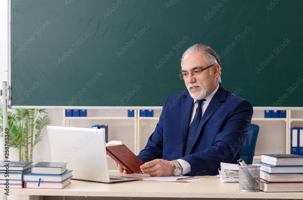 Aged male teacher in front of chalkboard Aged male teacher in front of chalkboard