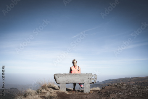 Young woman sitting on a bench at a beautiful viewpoint photo