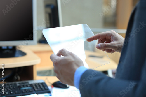 Businessman hand with transparent tablet and pc computer.