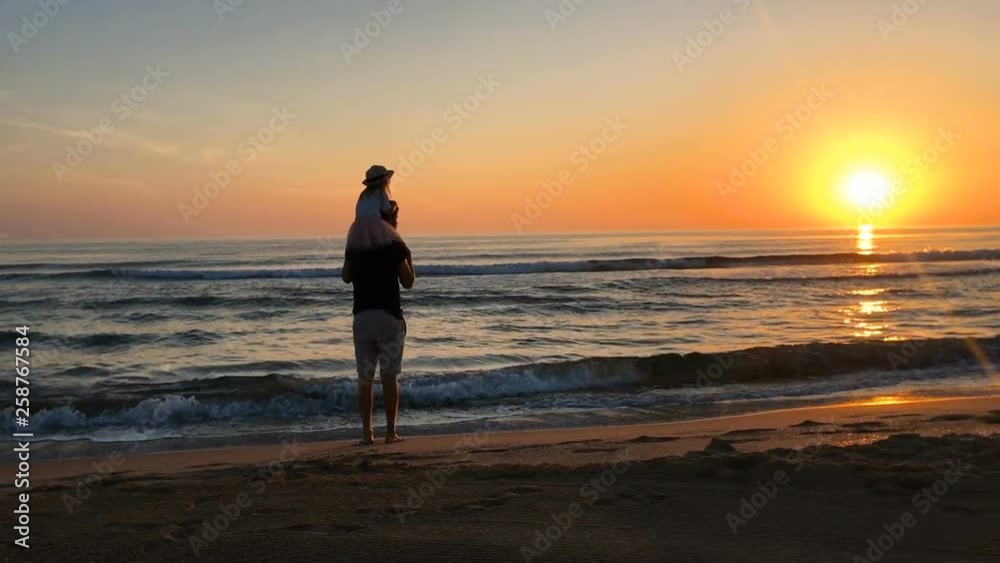 Father and daughter standing on the seashore at sunset. Father and daughter standing on the seashore at sunset.
