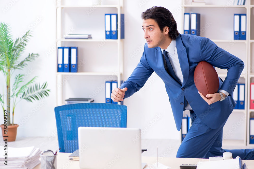 Young handsome businessman with rugby ball in the office Young handsome businessman with rugby ball in the office