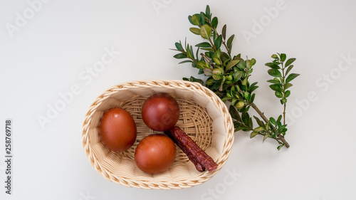 Koszyk wielkanocny z jajkami, kabanosem i bukszpanem na białym tle