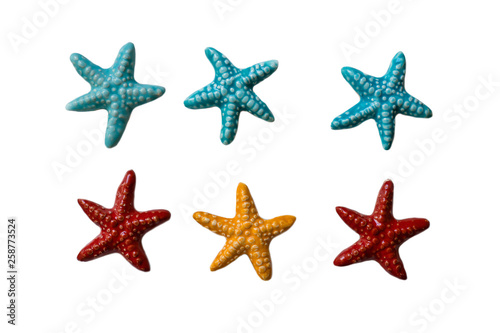 Handmade ceramic decorations representing colored sea stars on the white isolated background.