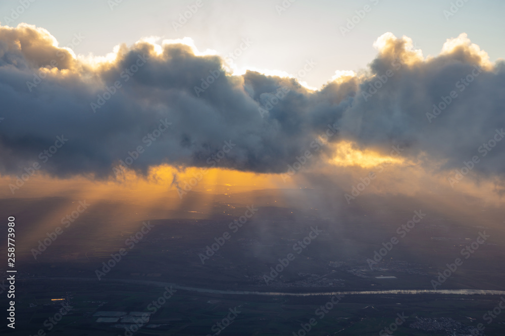 Beams of sun going through cloud onto evening land