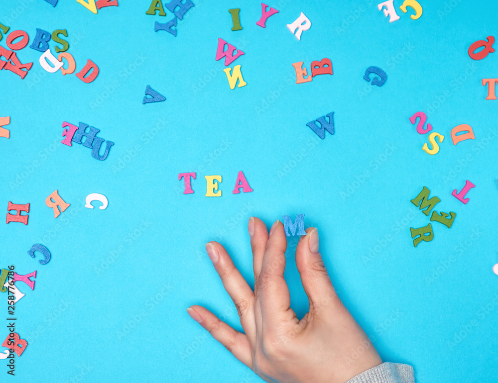 female hand and multicolored wooden letters of the English alphabet