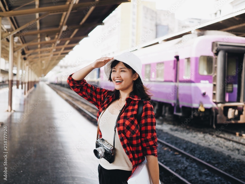 Happy Asian woman traveler at train station.