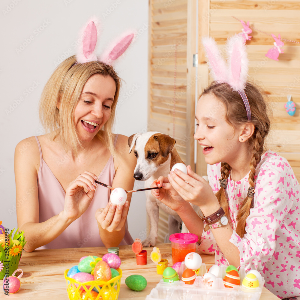Fototapeta Szczęśliwa kobieta z dzieckiem maluje Easter jajka