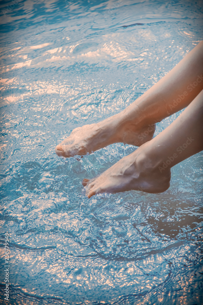 Summer vacation and holiday. Young woman wets feet in water.