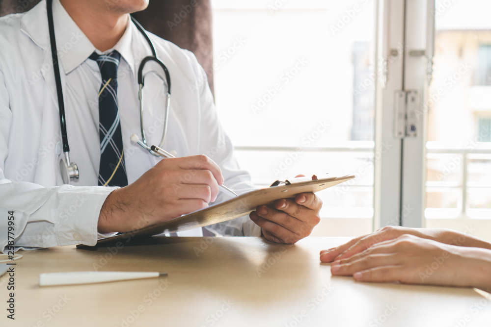 Close up hands of doctor taking note patient history to clipboard and giving diagnosis her disease. Close up hands of doctor taking note patient history to clipboard and giving diagnosis her disease.