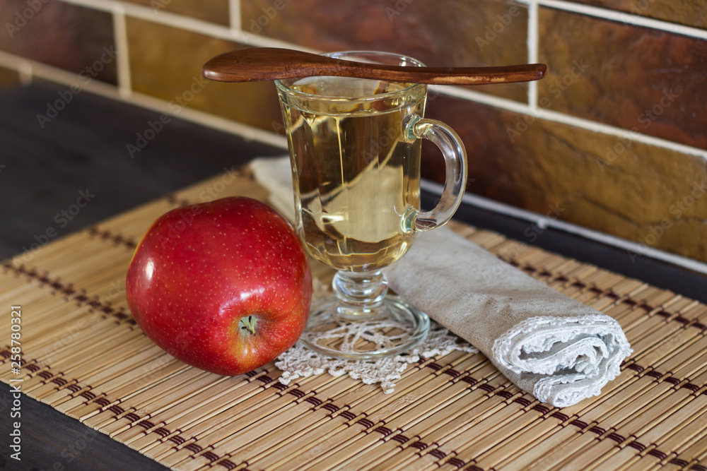 Fresh apple, drink fresh apple and a wooden spoon on a background of a brick wall. Selective focus.