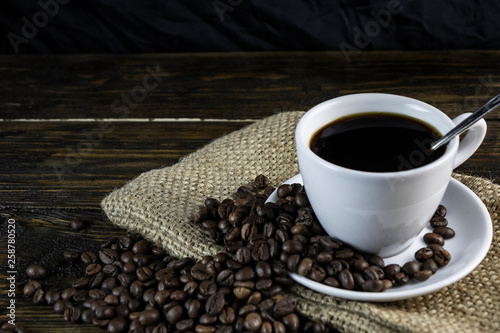 Cup of coffee and coffeCup of coffee and coffee beans on a rough wooden background.e beans on a rough wooden background.